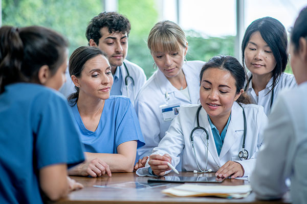 A female doctor is leading a learning session for her group of medical residents at the hospital.